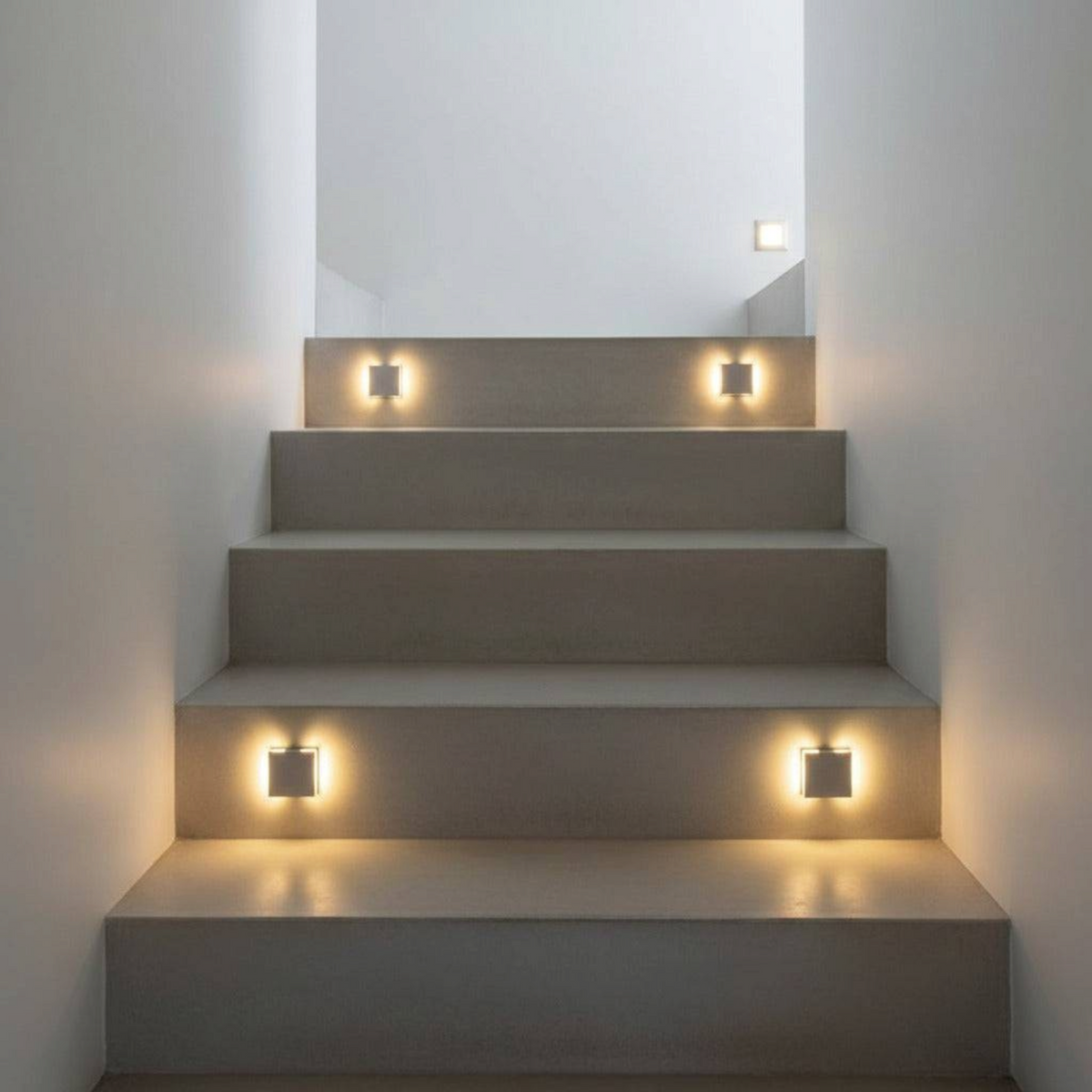 Ultra Beam Lighting Ltd square recessed LED stair lights in brushed aluminum casting a warm glow on indoor steps.