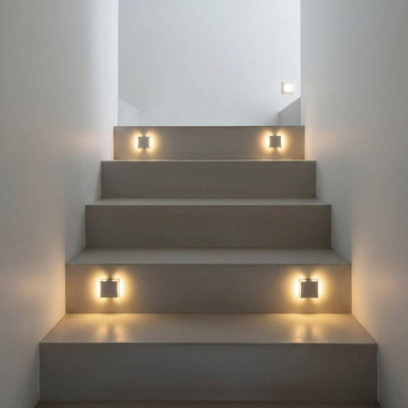 Ultra Beam Lighting Ltd square recessed LED stair lights in brushed aluminum casting a warm glow on indoor steps.