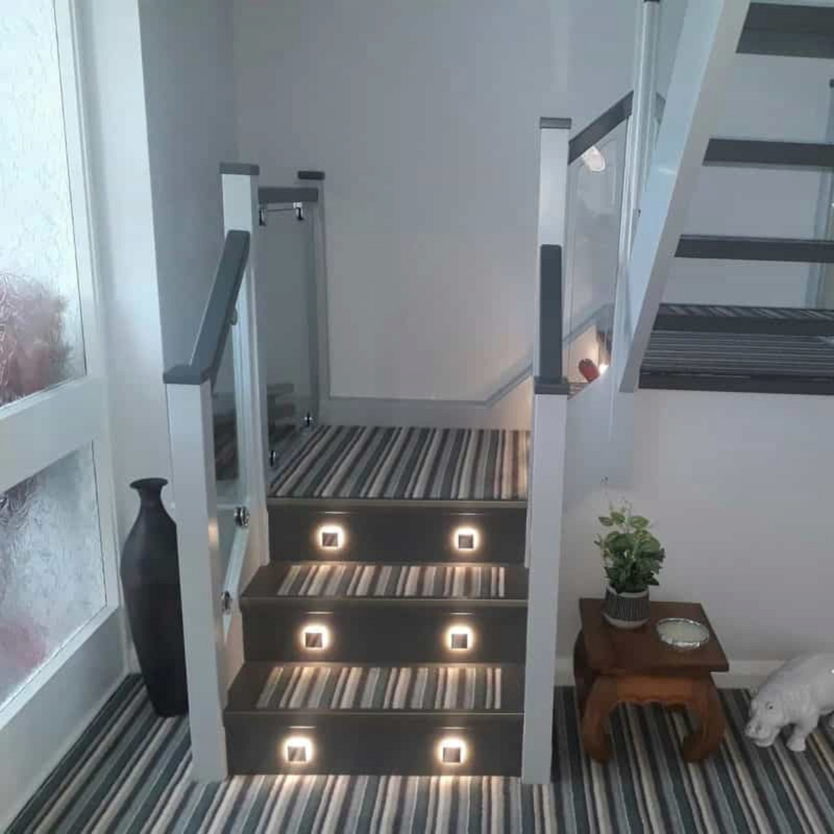 Ultra Beam Lighting Ltd square recessed LED step lights installed on a modern staircase with striped carpet