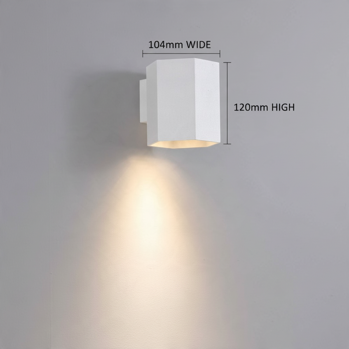 Ultra Beam Lighting Ltd white hexagonal LED wall downlight casting a warm downward beam on a grey wall.