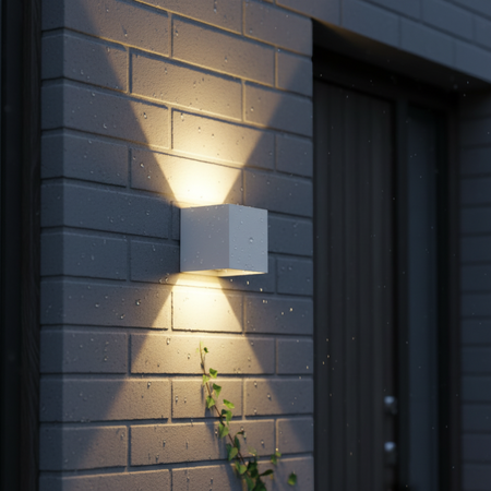 Ultra Beam Lighting Ltd white 6W LED up and down outdoor wall light casting a warm glow on a rainy brick wall