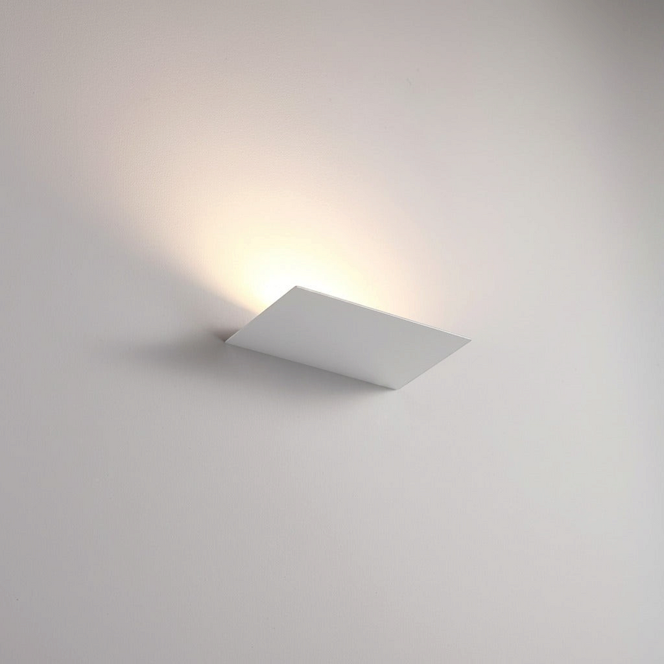 Ultra Beam Lighting Ltd 12W white LED indoor uplight wall sconce casting a warm ambient glow in a modern hotel lobby.